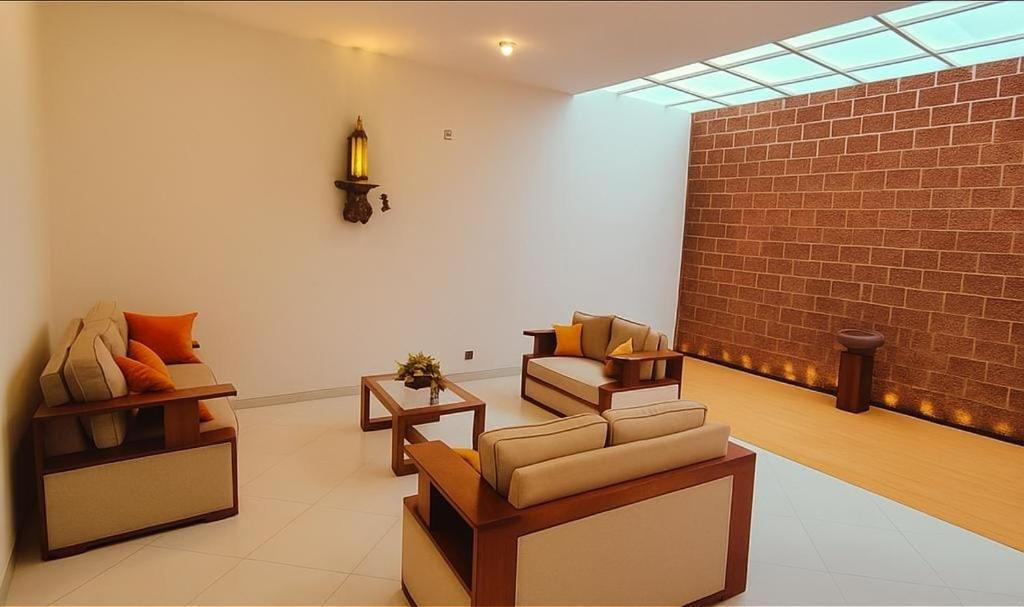 a living room with couches and a brick wall at Villa Lovi Tree in Katunayake
