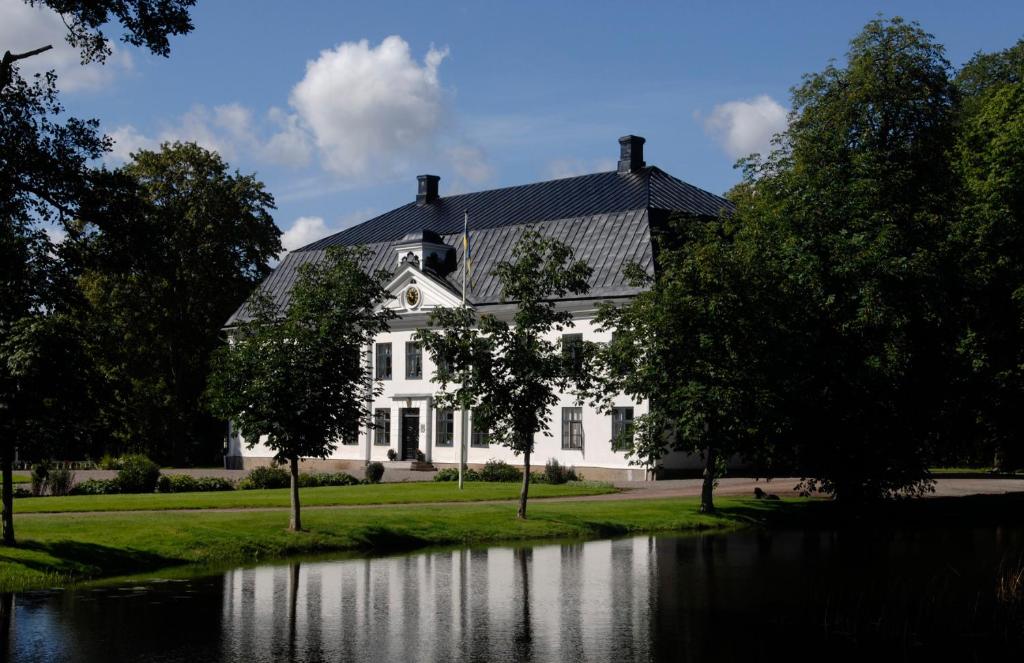 a white house with a pond in front of it at Moholms Herrgård in Moholm