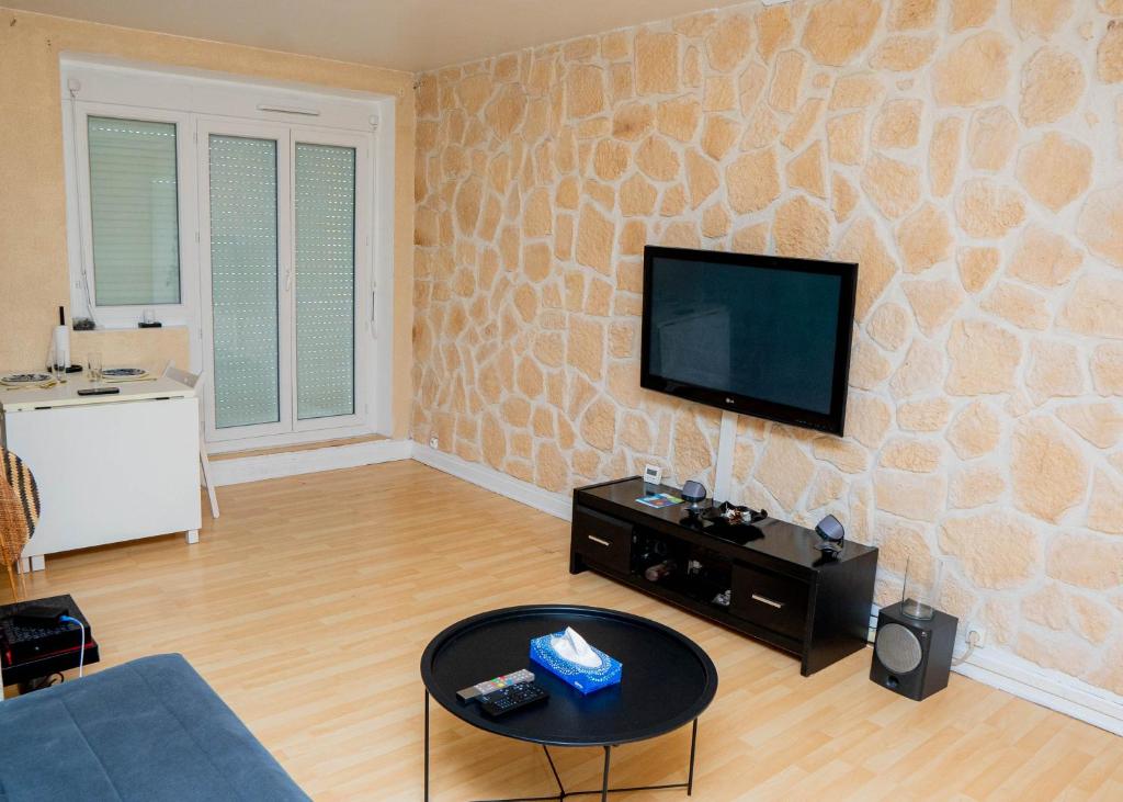 a living room with a tv on a stone wall at L'écrin citadin in Nanterre