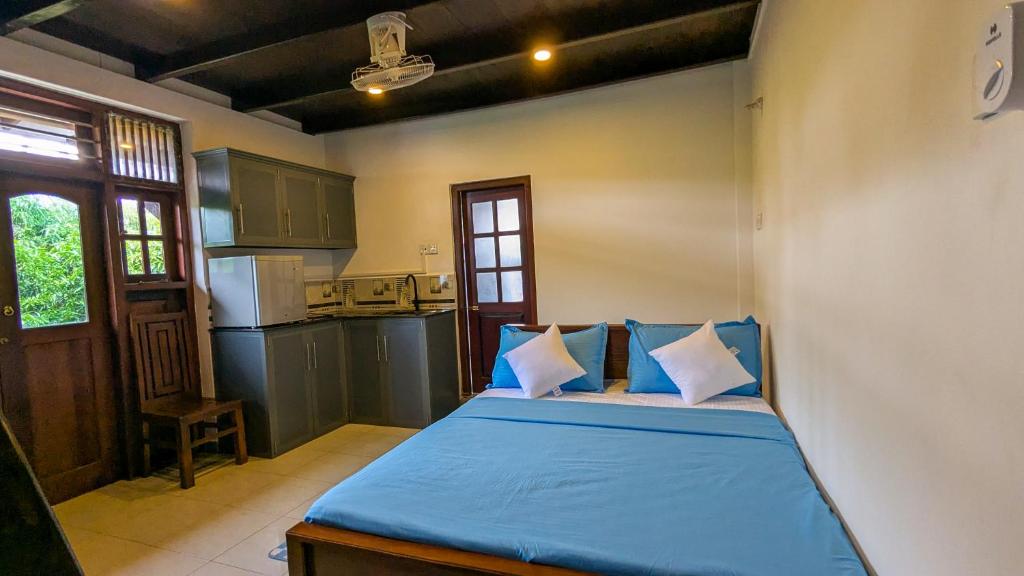 1 dormitorio con 1 cama con sábanas azules y cocina en Silva Nest - Galle, en Galle