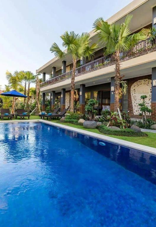 チャングーにあるThe Belong Canggu Bali By SDM Managementのヤシの木が茂る建物の前にあるスイミングプール