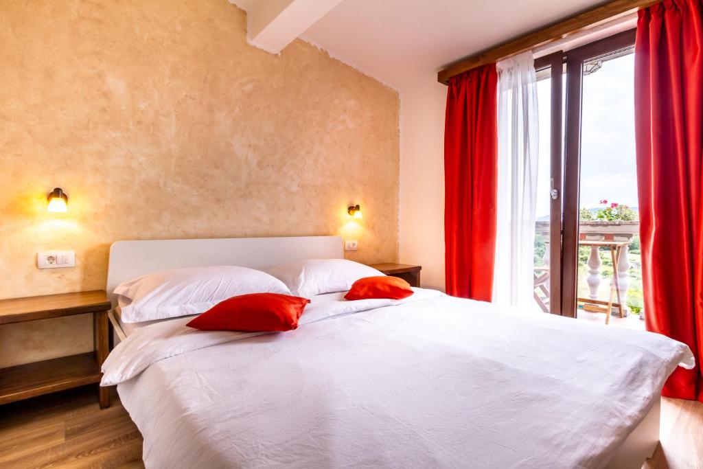 a bedroom with a bed with red curtains and a window at B&B Tonivale in Skrbčići