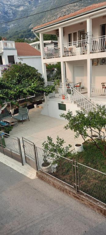 a large white building with a patio in front of it at Apartmani Palma in Sutomore