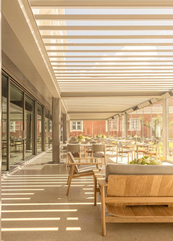 A bright glazed dining terrace offers tables beneath a slatted overhead canopy.