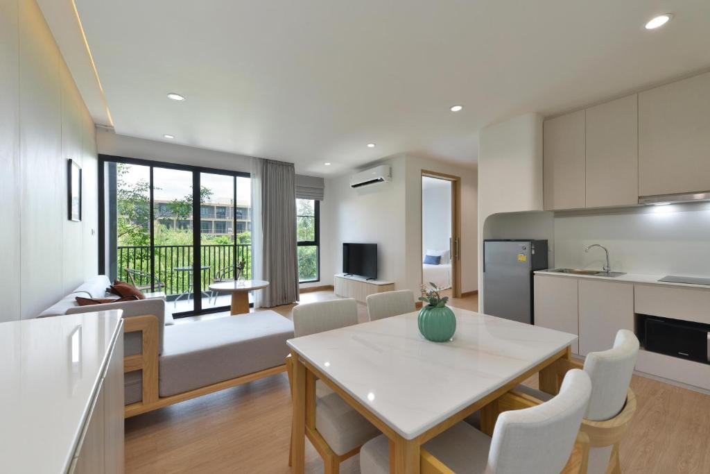 An open-plan apartment combining a lounge, dining table and kitchenette.