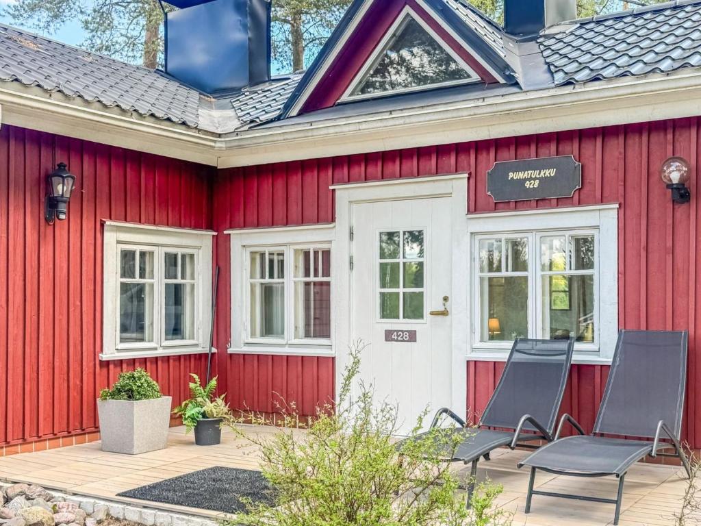a red house with two chairs in front of it at Holiday Home Punatulkku by Interhome in Hirsjärvi