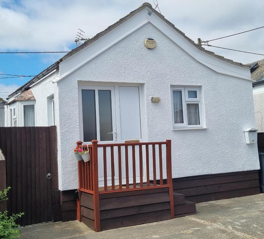 une maison blanche avec un banc devant dans l'établissement Sandy Cottage, à Clacton-on-Sea