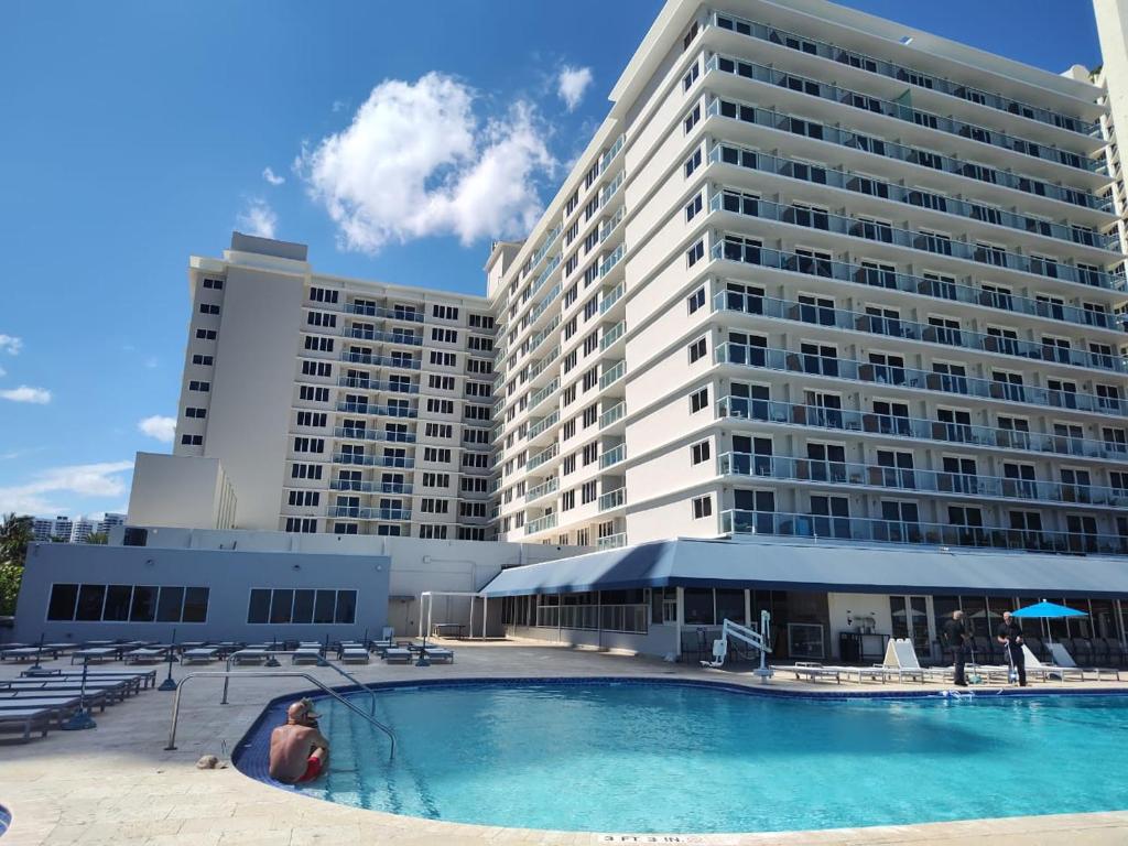 a woman sitting in front of a large building at Estudios con y sin balcón en Sunny Isles Beach in Sunny Isles Beach