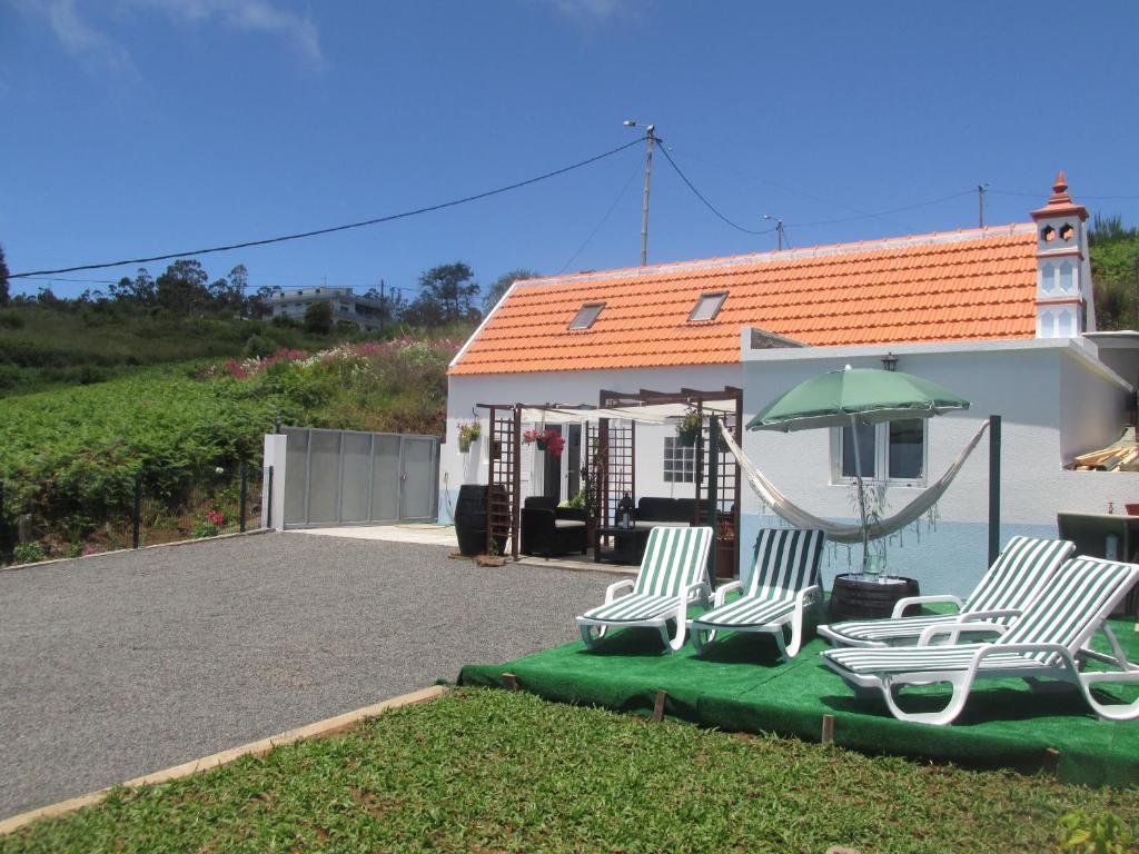 two chairs and a hammock in front of a house at Casa Formiga in Fajã da Ovelha