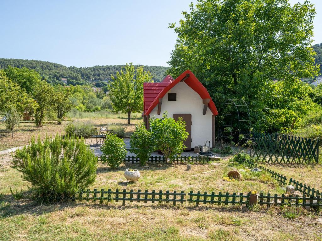 a small house with a red roof in a garden at Holiday Home Little Castle by Interhome in Skradin