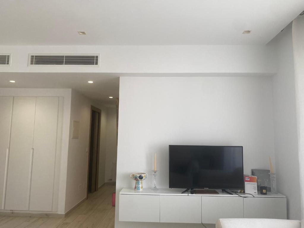 a living room with a flat screen tv on a white cabinet at White cosy apartment in La Marsa