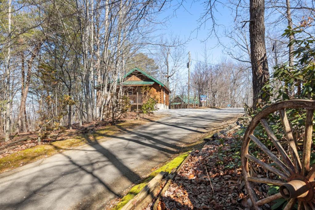 a road with a wooden barn next to a forest at Forever Yours by American Patriot Getaways in Cove Creek Cascades