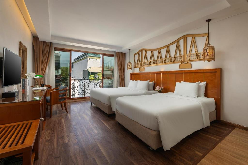 two beds in a hotel room with a balcony at Hanoi Golden Holiday Hotel in Hanoi