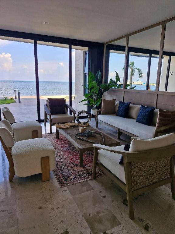 a living room with a couch and chairs and the ocean at Beautiful Studio Puerto Morelos in Puerto Morelos