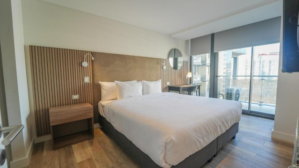 a bedroom with a large bed and a large window at Spot Suites in Santiago