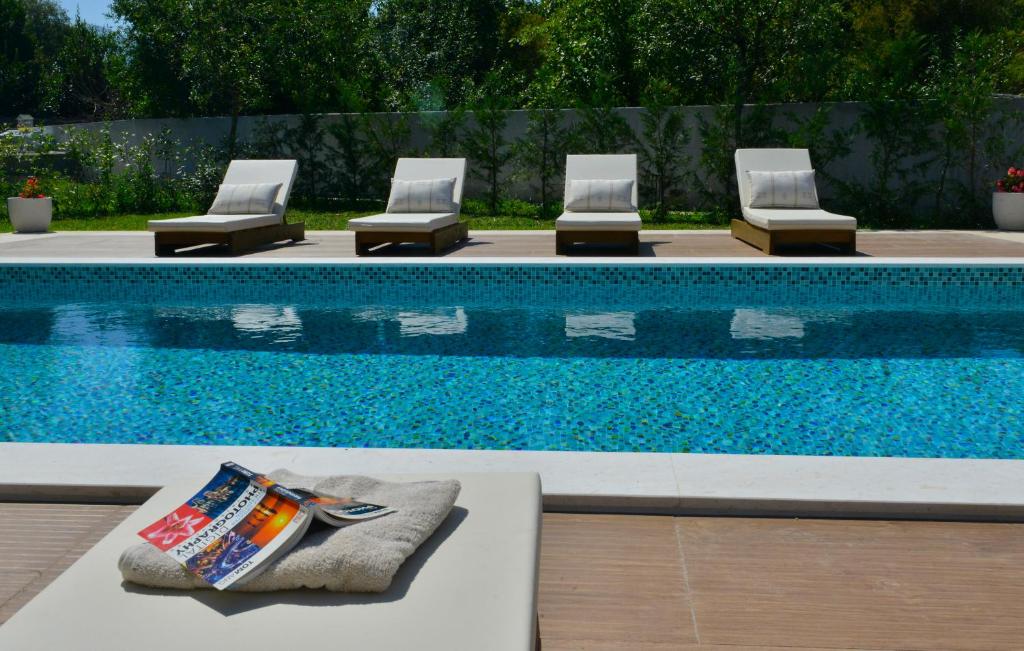 a swimming pool with four lounge chairs next to it at Villa Jovanovic in Tivat