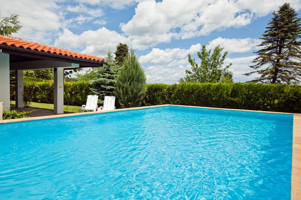 una gran piscina azul con 2 sillas blancas en SanMarco Villas, en Kranevo