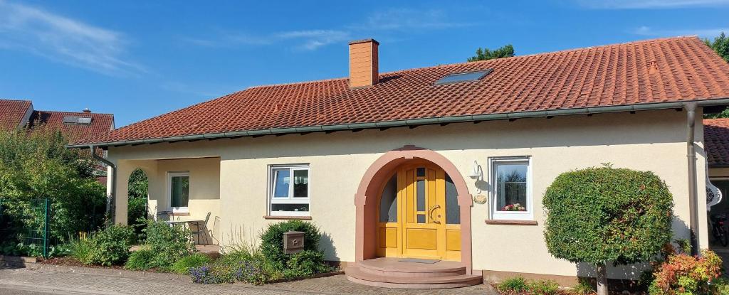a small house with a yellow door in a yard at Ferienwohnung Catus in Rheinzabern