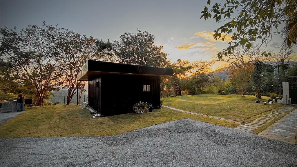 a small black shed sitting on top of a field at Chale Container no Centro de Petrópolis in Petrópolis