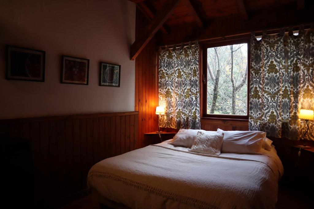 a bedroom with a bed and a window with curtains at Hosteria Las Cartas in San Carlos de Bariloche