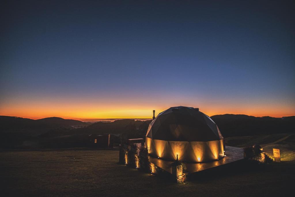 a tent sitting on top of a mountain at sunset at Refúgio nas Nuvens, Domo Omega Luxuoso com Fogo de Chão e Hidro Panorâmica in Rancho Queimado