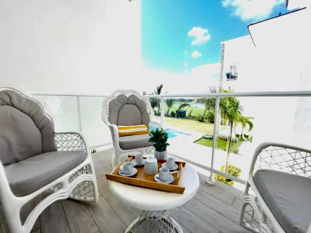 プンタ・カナにあるComfortable 1BDR in Cana Pearl with Lake/Golf Viewのバルコニー(椅子2脚、テーブル、トレイ付)
