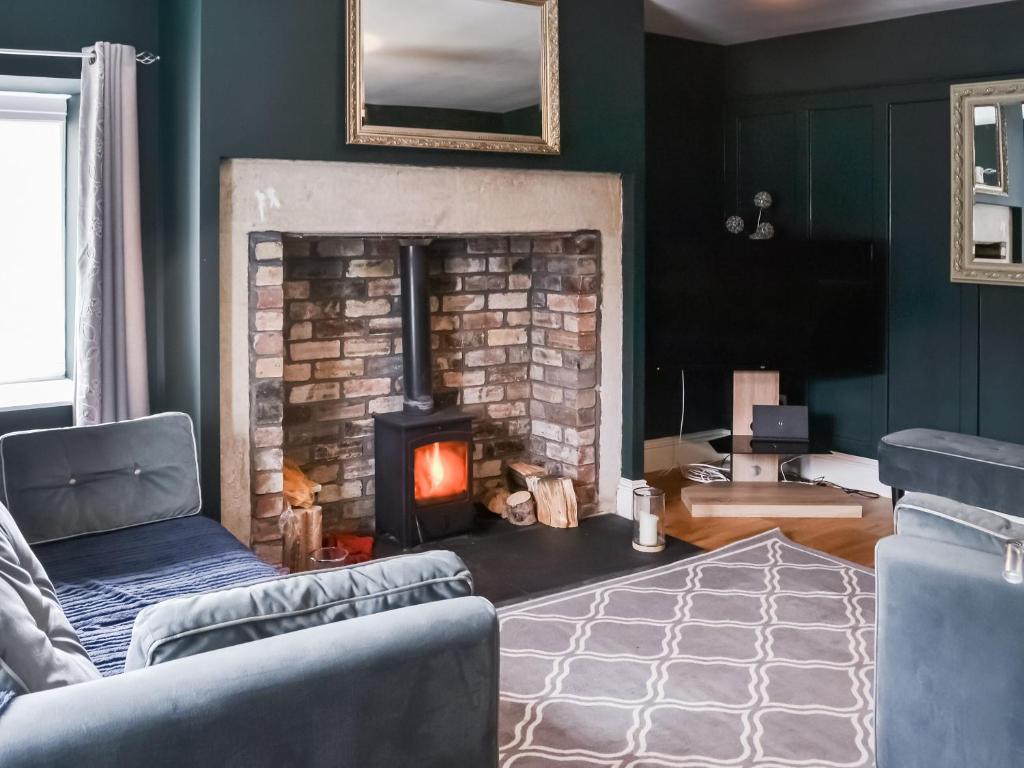 a living room with a fireplace and a couch at Prospect Cottage in Catton