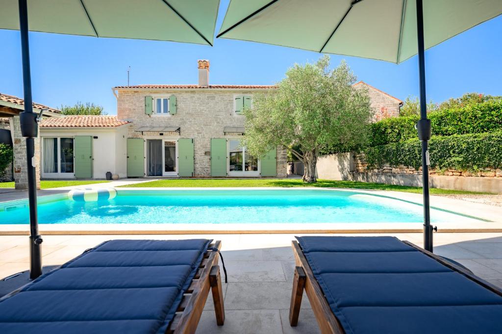 a swimming pool in front of a house with an umbrella at Villa Veromi with private pool in Istria in Orbani