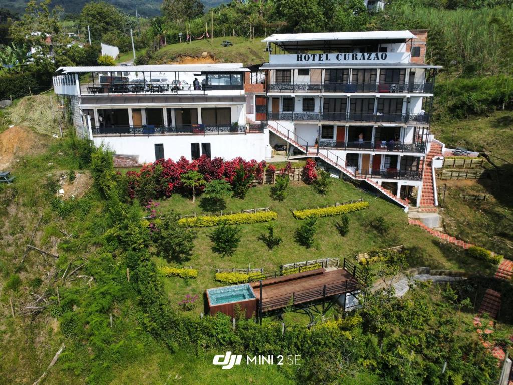 a building with a garden on the side of a hill at Hotel Curazao Natural Living cerca a charcos naturales y tobogán extremo in Cocorná