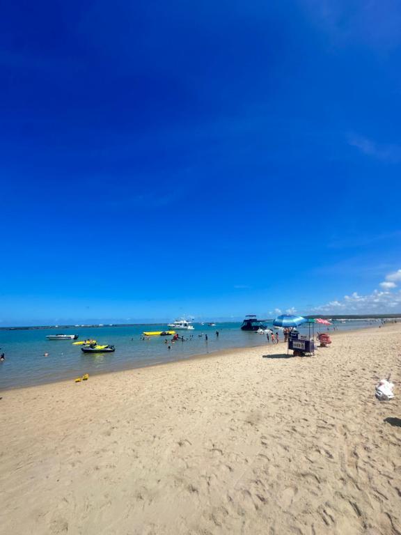 a beach with people and boats in the water at Barra Bali Resort in Barra de São Miguel