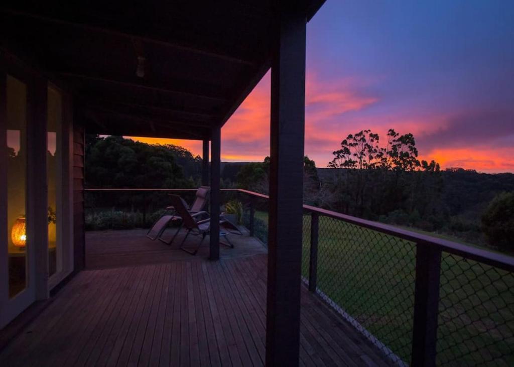 een zonsondergang op een veranda met een stoel op een terras bij Cape Cottages - Ollies View in Tanybryn