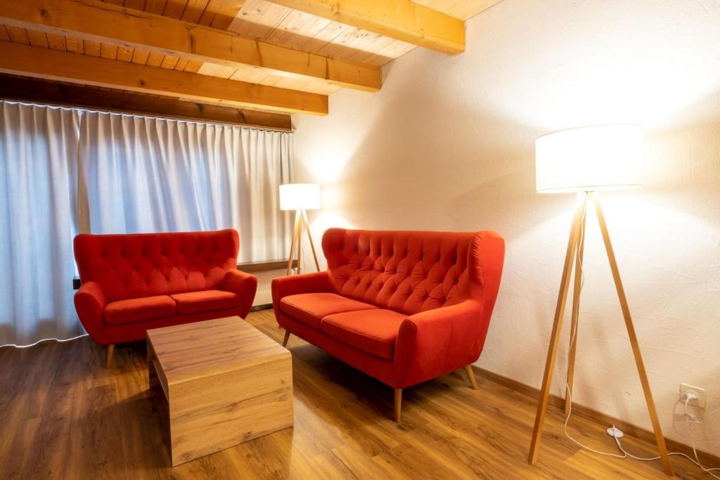 a living room with two red chairs and a lamp at Edelweiss Pany in Pany