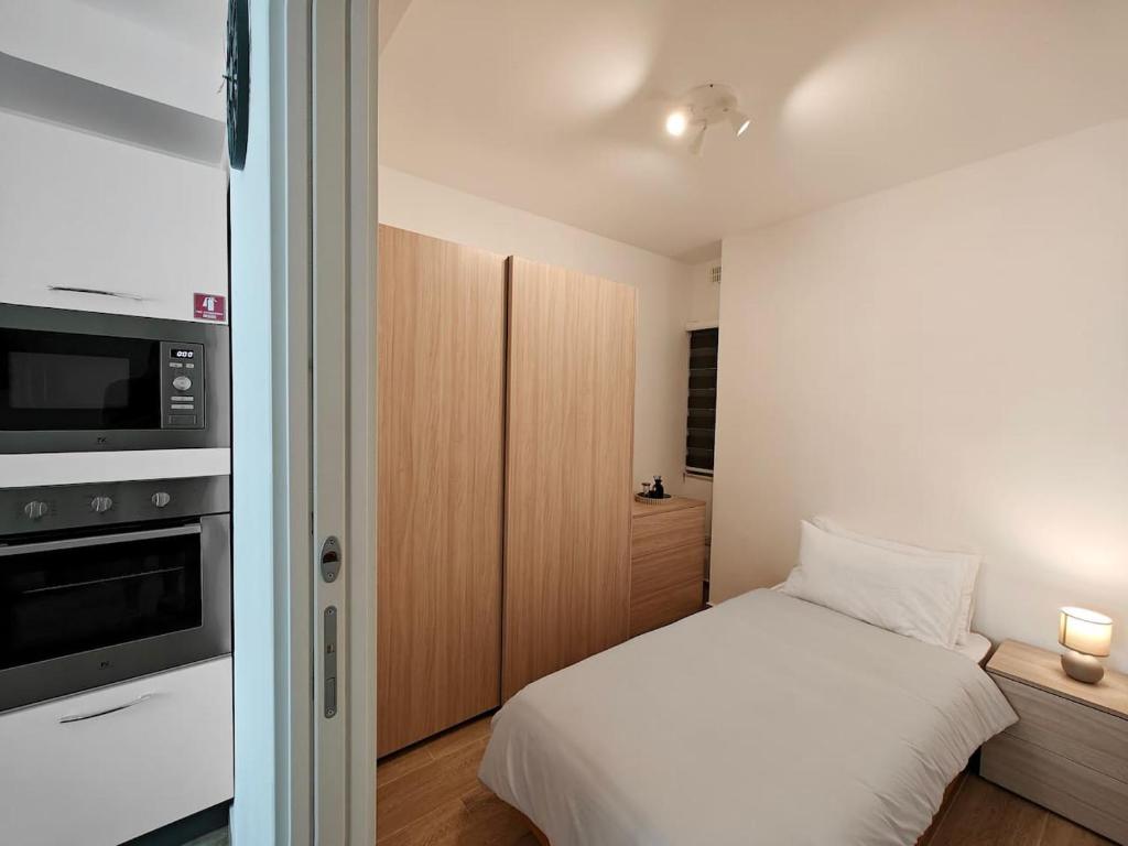 Dormitorio pequeño con cama y microondas en The Urban Nest, en Tal-Pietà