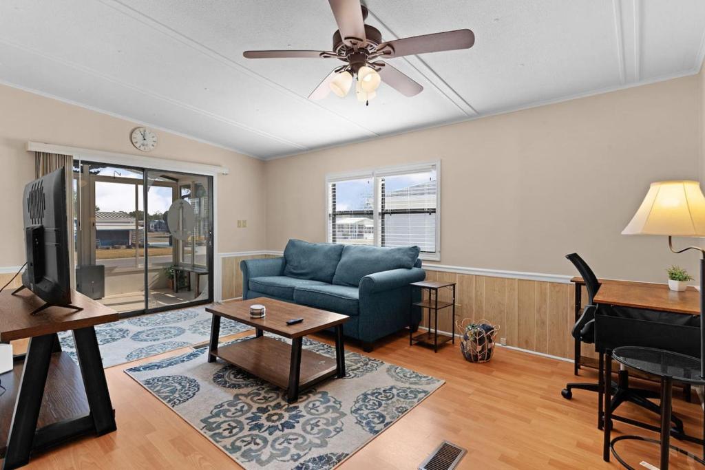 a living room with a blue couch and a piano at Sunlit 2BR with Lanai on Golf Cart Path in Lady Lake