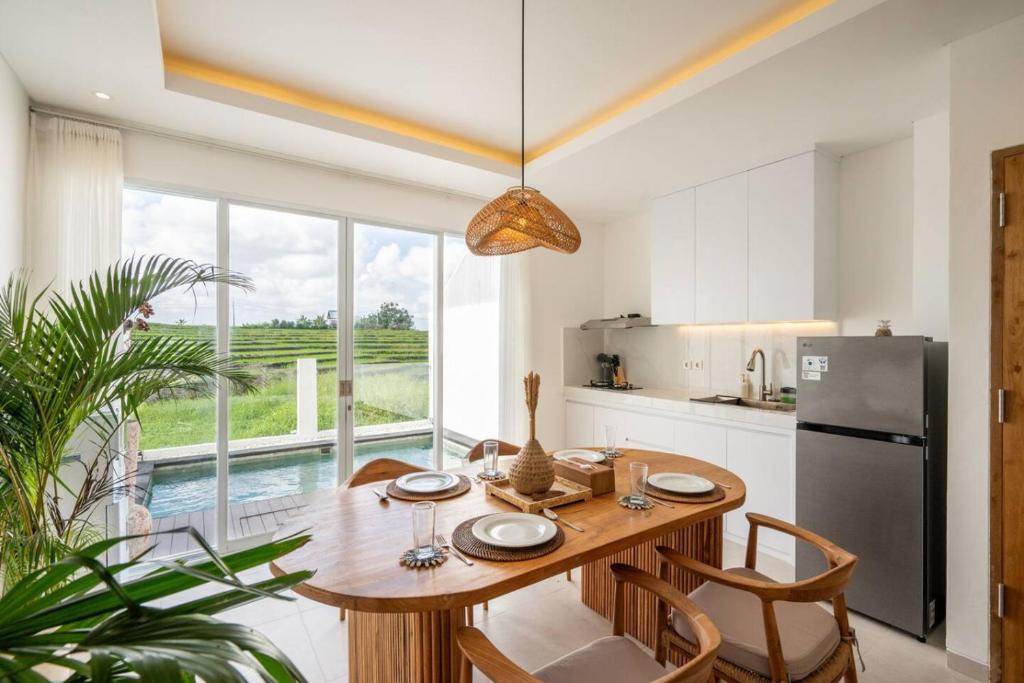 a kitchen with a wooden table and a refrigerator at Sunrise Bliss 13 Ricefield View Private Pool Villa By Bali Bliss Properties in Dalung