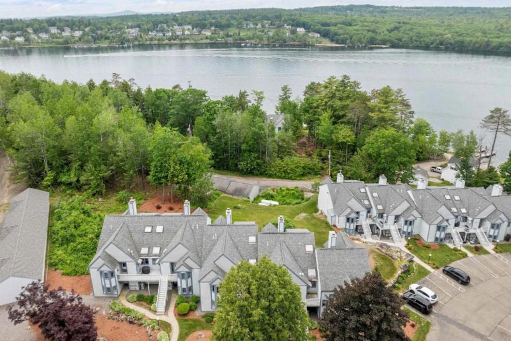 an aerial view of a row of houses next to a lake at 3BR Lake Winnipesaukee Condo with Sandy Beach in Laconia