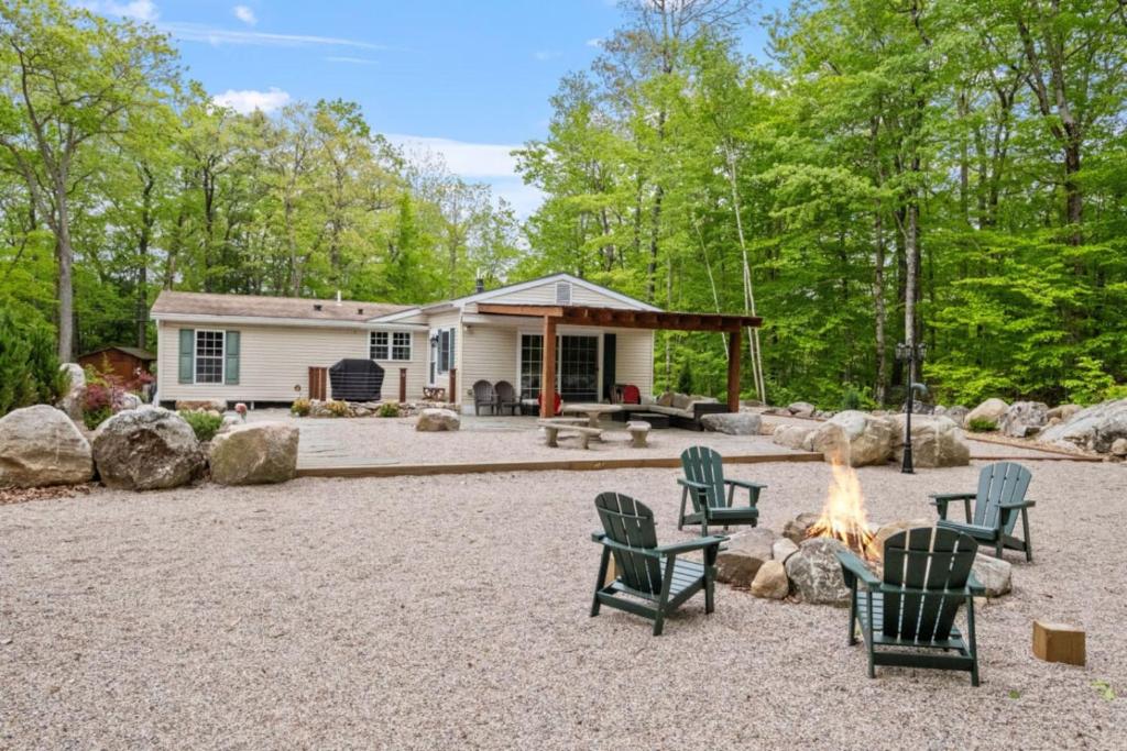 a patio with chairs and a fire pit in front of a house at Cozy 3BR with Firepit and Boat Slip Option in Moultonborough