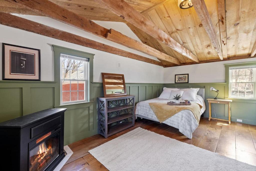 a bedroom with a bed with a fireplace and a wooden ceiling at Rustic Beauty, Fireplace, Cows & Mountain Views in Gilmanton