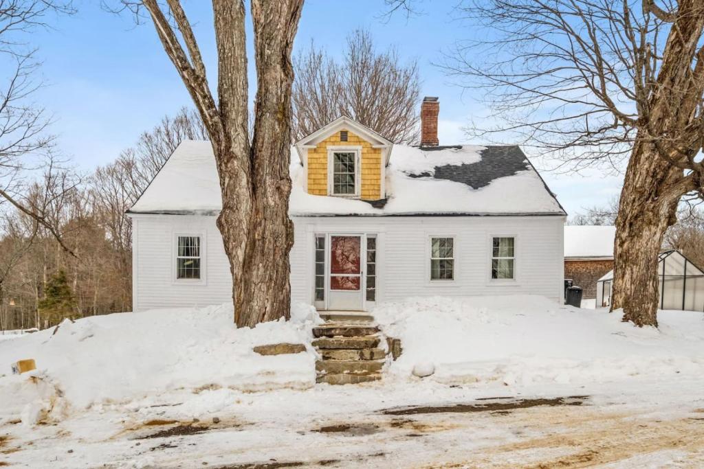 a white house with snow on the ground at Private Farm Loft - Tub, Animals & Pasture Views in Gilmanton