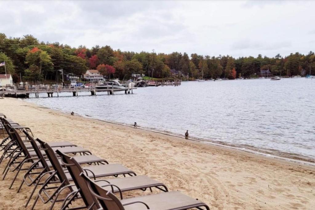 a group of chairs on a beach next to the water at Walk to Concerts Beach with Pool View in Gilford