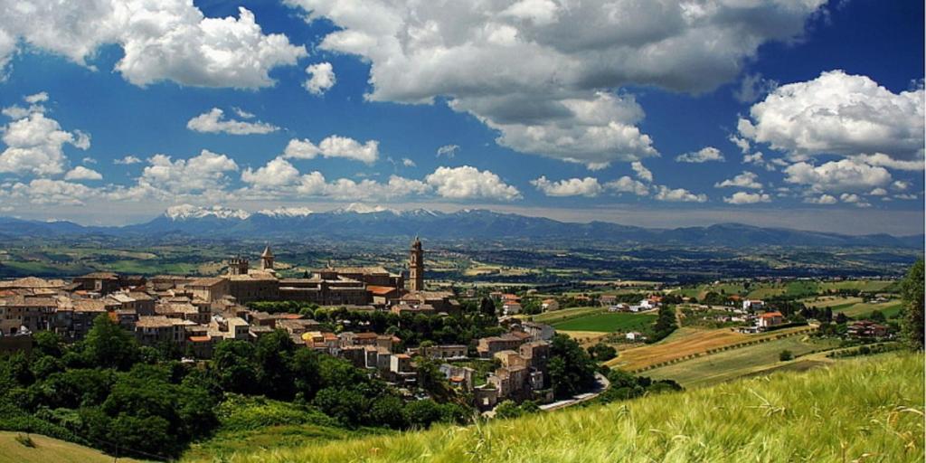 une ville sur une colline avec des montagnes en arrière-plan dans l'établissement Marche Hills, à Morrovalle