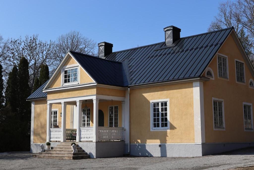 a yellow house with a black roof at Private mansion for family, friends or colleagues 