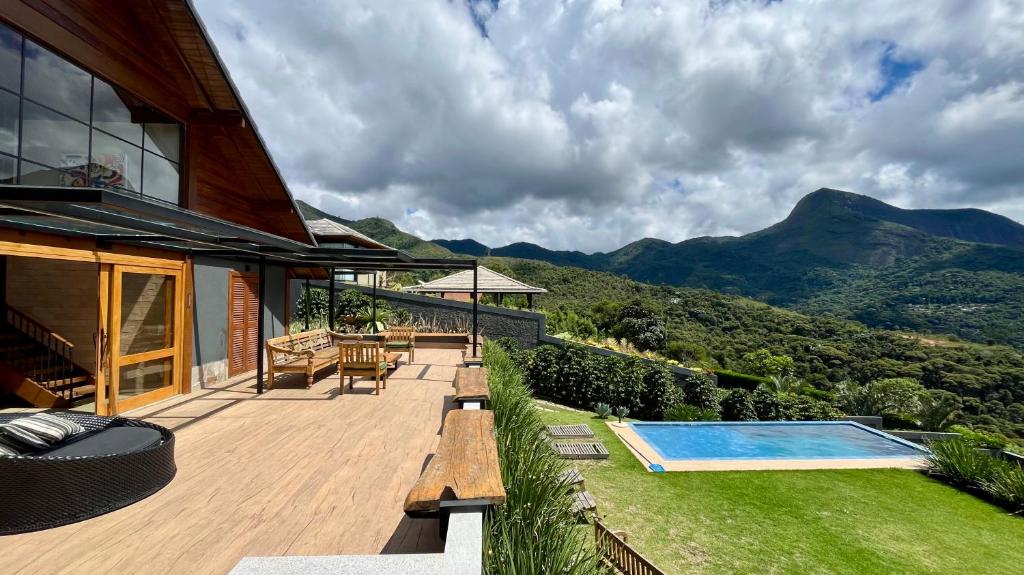 a house with a deck and a swimming pool at Casa 02 Monte Boa Vista - Casa de 4 Suítes com Vista Deslumbrante in Teresópolis