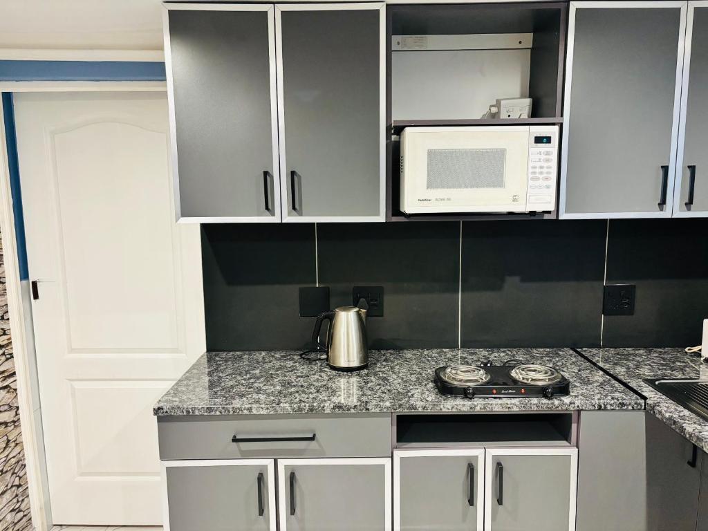 a kitchen with white cabinets and a white microwave at Brown Accomodation in Cape Town