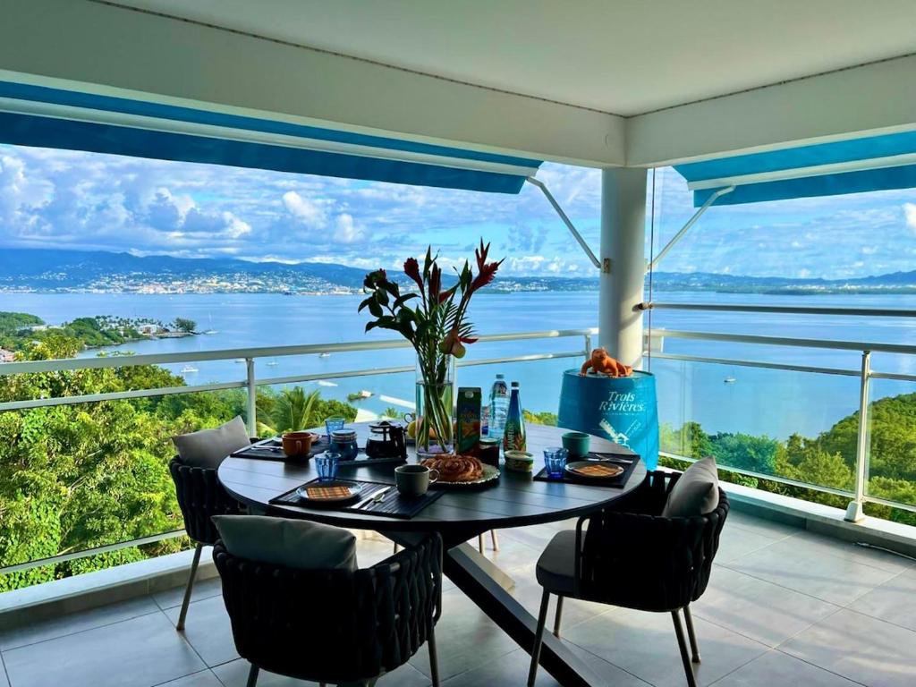 a dining room with a table and chairs and a view of the ocean at L'Ecrin de la Baie in Les Trois-Îlets