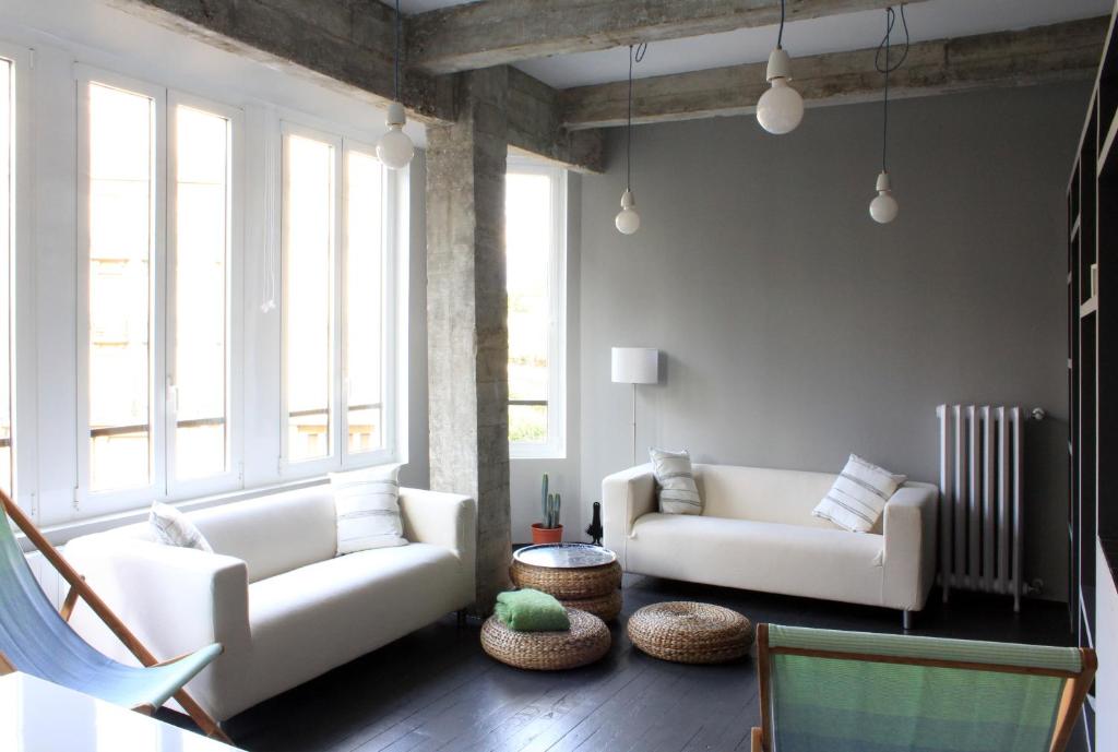 una sala de estar con 2 sofás blancos y ventanas grandes. en San Sebastian playa Zurriola, en San Sebastián