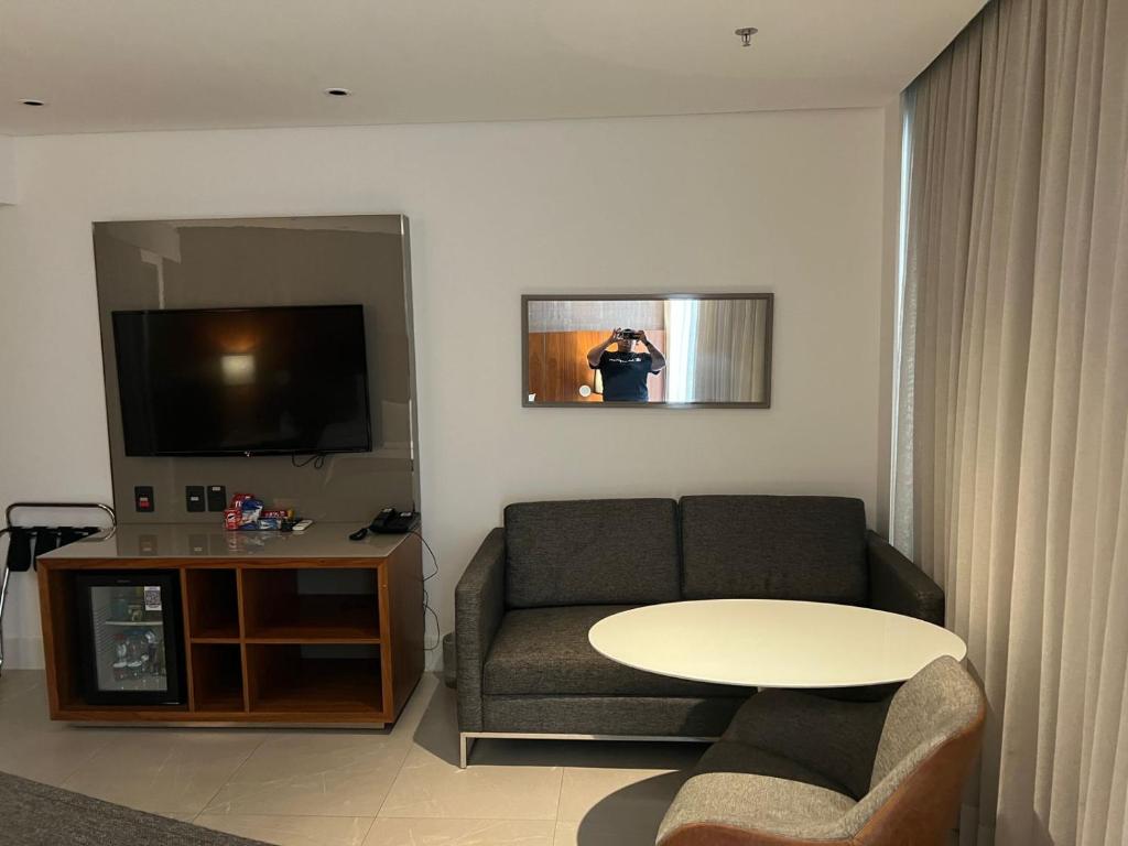 a living room with a couch and a table and a tv at Hotel Nacional in Rio de Janeiro