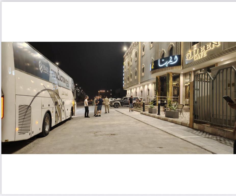 un bus garé sur le bord d'une rue la nuit dans l'établissement المها للشقق المخدومة, à Al Thybiyah