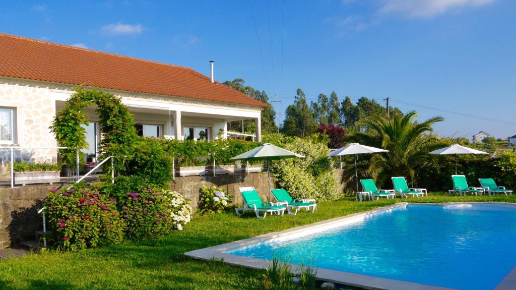 a house with a swimming pool with chairs and umbrellas at Quinta das Leiras - Rubiães in Paredes de Coura