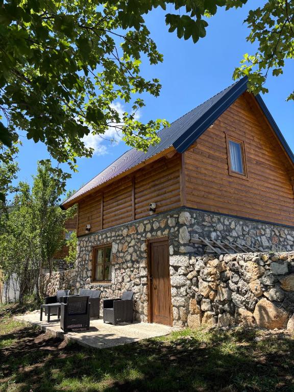 a stone building with a wooden door and chairs in front at Arhetip, Djedova Villa in Žabljak
